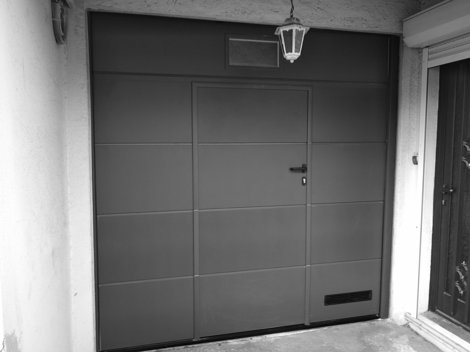 Noyer Menuiseries | Pose de menuiseries extérieures - Porte de garage grise avec entrée | Saint-Clément-de-la-Place - Beaucouzé - Bécon-les-Granits